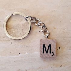 a metal keychain with the letter m on it sitting on a marble surface