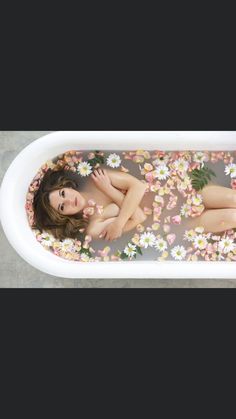 a woman laying in a bathtub filled with flowers