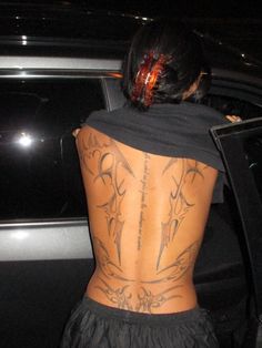 the back of a woman's body with tattoos on it