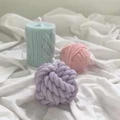 two balls of yarn sitting on top of a bed next to a knitted ball