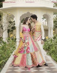 a man and woman standing next to each other in front of a gazebo