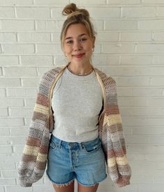 a woman standing in front of a brick wall with her hands in her pockets and smiling