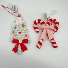 two candy canes and a christmas ornament on a white surface with a red ribbon