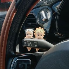 two cartoon figures are sitting on the dashboard of a car, next to a steering wheel