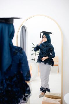 a woman in a graduation gown is talking on her cell phone while looking at herself in the mirror