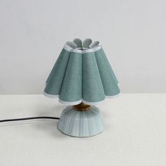 a lamp that is sitting on top of a white table with a black cord attached to it