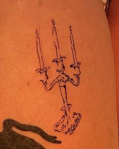 a woman's leg with a tattoo on it that has a drawing of a man holding candles