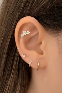 a woman wearing three different types of ear piercings