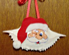 a santa clause ornament hanging from a wooden table with a red ribbon on it