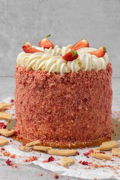 a red velvet cake with white frosting and strawberries on top, surrounded by crackers