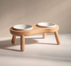 two white bowls sit on a wooden stand