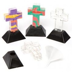 four plastic crosses on black bases with colored designs and shapes in the middle one is shaped like a cross