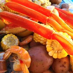 an assortment of vegetables and fruits are shown in this close - up photo, including carrots, corn, potatoes, and shrimp