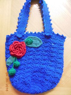 a blue crocheted bag with a flower on it