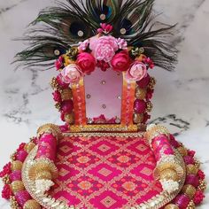 a pink and gold decorated chair with peacock feathers on the back, sitting on a marble surface