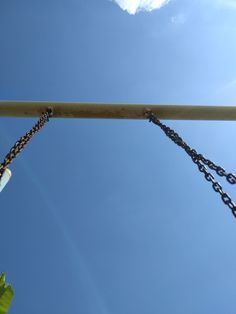 a metal chain hanging from the side of a wooden pole with blue sky in the background