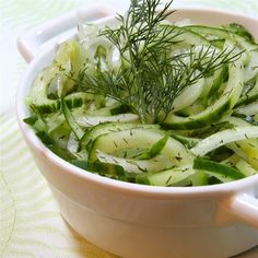 a white bowl filled with sliced cucumbers and herbs