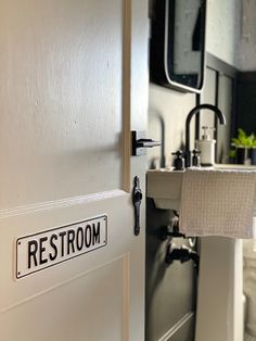 a restroom door with a sign that says restroom on it and a sink in the background