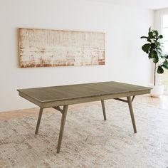 a wooden table sitting on top of a rug in front of a large white wall