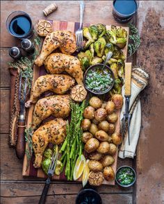 a wooden table topped with chicken, potatoes and veggies