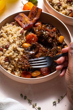 a person holding a fork over a bowl of food with rice and bacon on the side