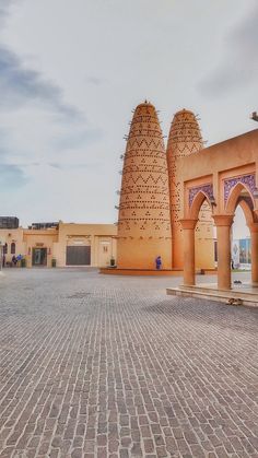 an archway in the middle of a brick courtyard with arches and doorways on either side