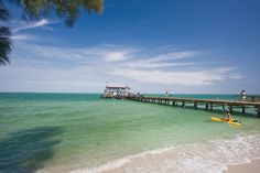 two people are kayaking in the ocean near a pier with a boat on it