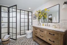 a bathroom with black and white tile flooring and yellow flowers on the counter top