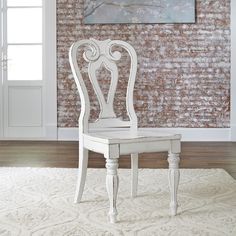 a white chair sitting on top of a rug in front of a wall with a painting