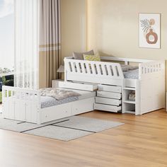 a white bed with drawers underneath it in a room next to a wooden floor and window