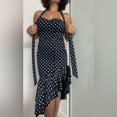 a woman in a polka dot dress is holding on to her tie