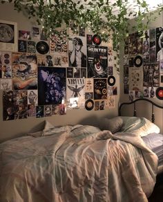 an unmade bed in a bedroom with lots of posters on the wall above it