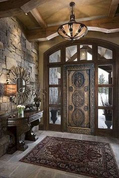 a foyer with stone walls and an ornate door that leads to the entry way, along with a large rug on the floor