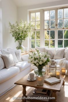 a living room with white furniture and flowers in vases on the coffee table next to the couch