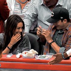 a man and woman sitting at a red table in front of a group of people