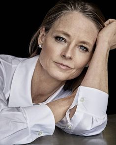 a woman sitting at a table with her hands on her head and looking off to the side