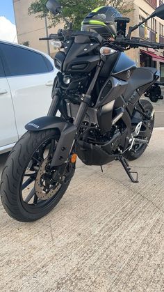 a black motorcycle parked in front of a white car