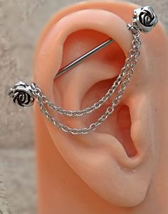 a pair of ear piercings with chains attached to the back of them, sitting on top of a fake human's head