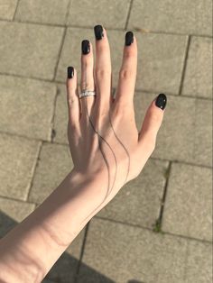 a woman's hand with black nail polish on it and a ring in the middle