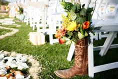 a cowboy boot with flowers in it sitting on the grass next to an empty chair