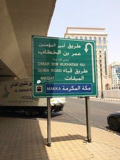 a green and white sign sitting on the side of a road next to a building