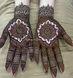 two hands with henna designs on them, one is showing the intricate pattern and the other has an elaborate design