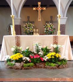 a table with flowers on it in front of a cross