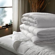 a stack of white pillows sitting on top of a bed