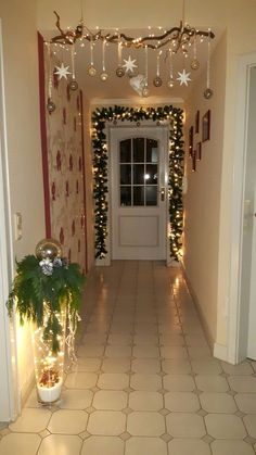 a hallway decorated for christmas with lights and potted plants on either side of the door