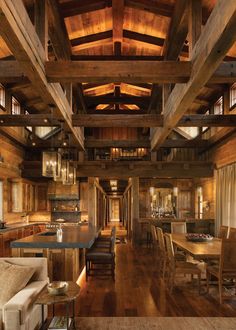 a kitchen and dining area in a log cabin style home with wood floors, ceiling beams, and large windows