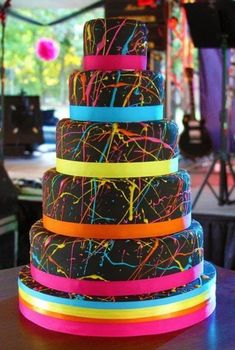 a multi - tiered cake is decorated with neon ribbons