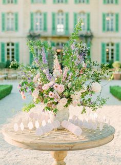 a vase filled with lots of flowers on top of a table in front of a building