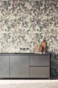 a kitchen with an artistic wallpaper pattern and wooden cutting board on the sideboard