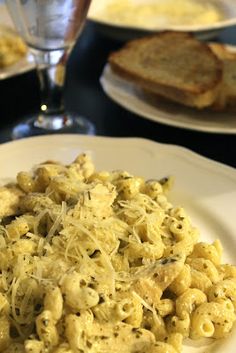 pasta with cheese and bread on a plate in front of wineglasses, toast